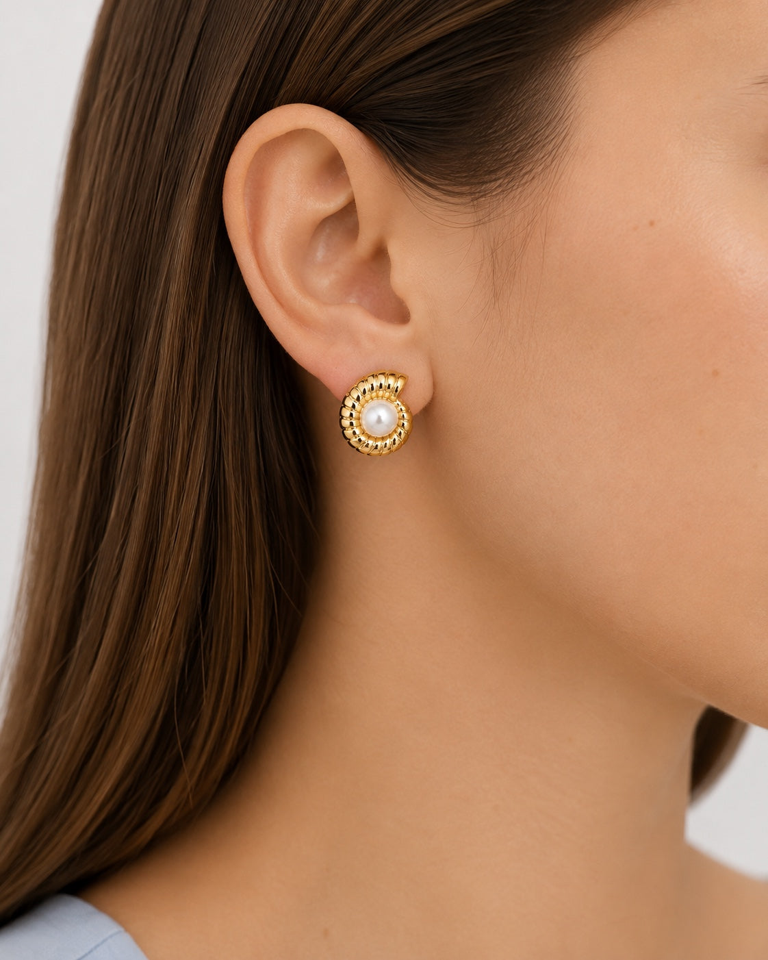 Model wearing gold-plated spiral earrings with pearl center