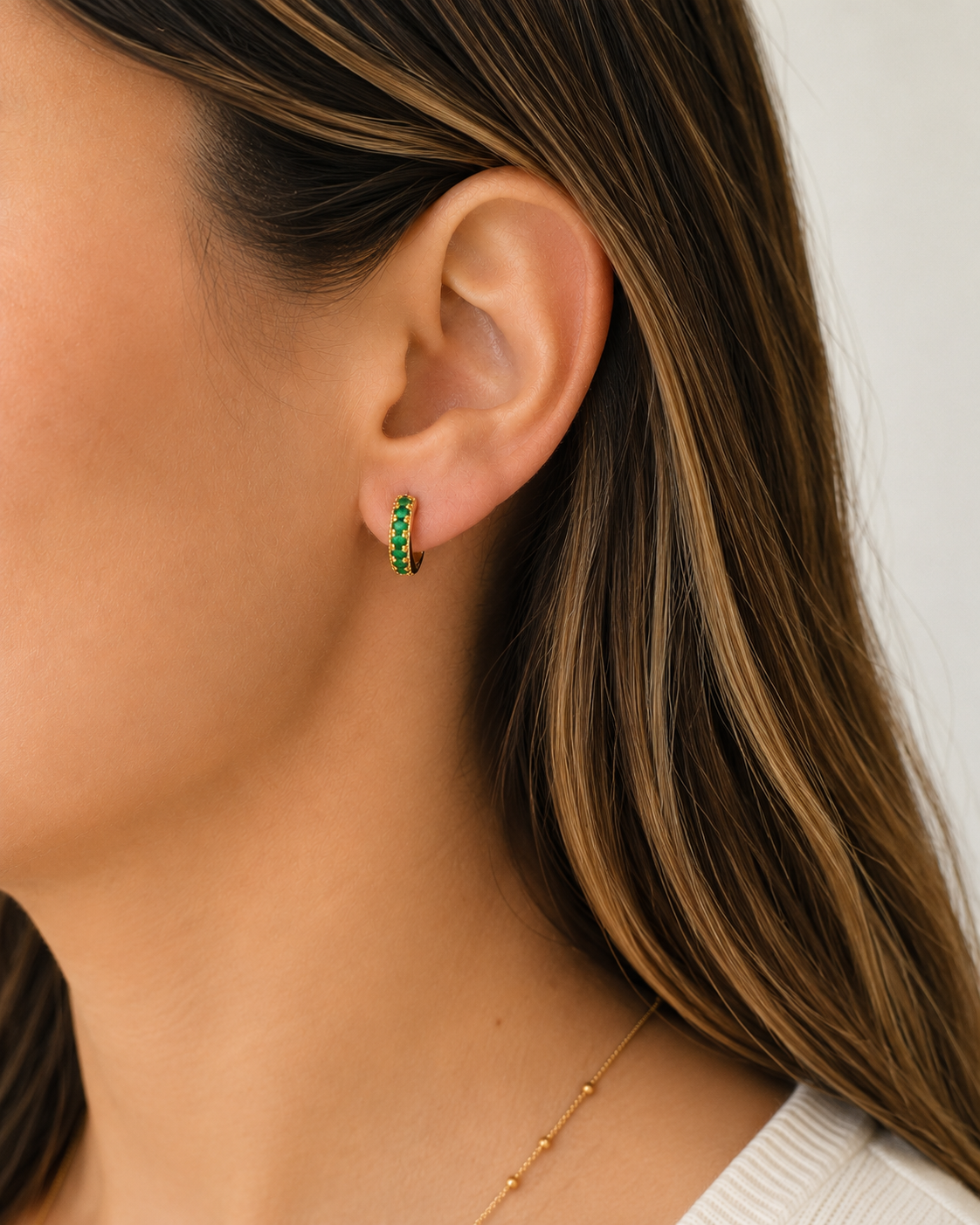 Model wearing COMPLIMENTI gold-plated green huggie earrings, 1.5 cm