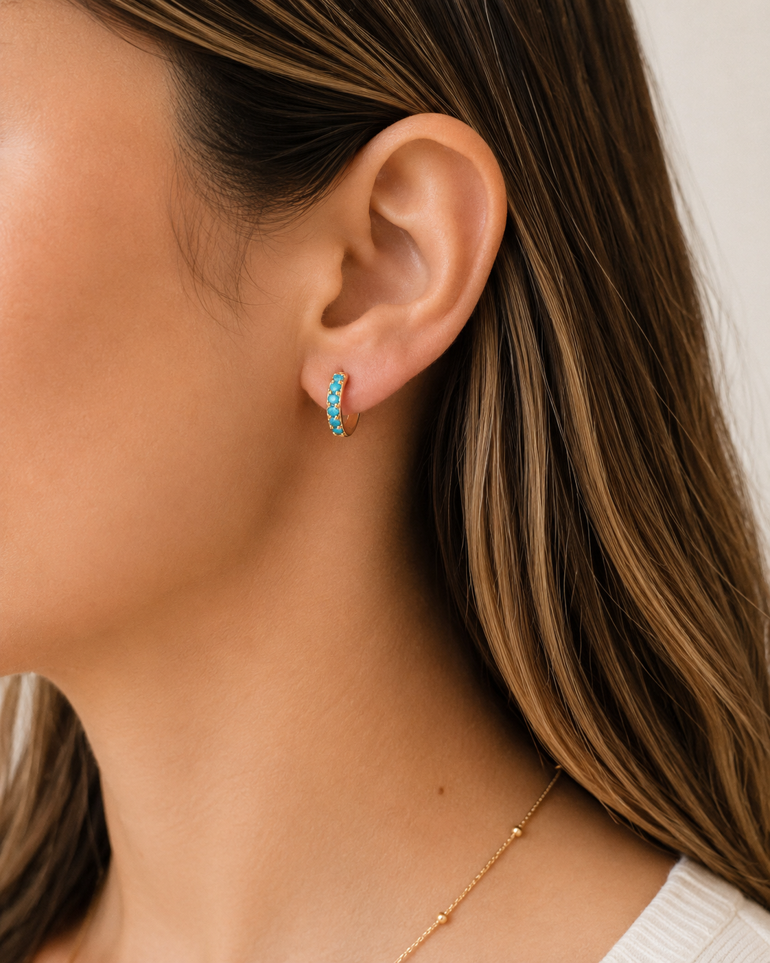 Model wearing COMPLIMENTI gold-plated turquoise huggie earrings, 1.5 cm